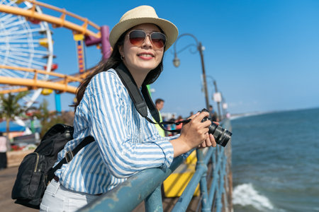 happy asian Japanese female photographer enjoying ocean scenery and california sun at waterfront...
