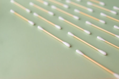 Flat plan of white cotton ear buds on green background with copy spaceの写真素材