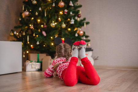 Charming girl on the background of burning lights and decorated Christmas treeの写真素材