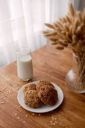 delicious freshly baked oatmeal cookies with chocolate on a wooden background with a glass of milk or yogurtの写真素材