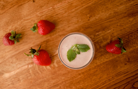 Strawberry smoothie or milkshake on a wooden background with fresh strawberriesの写真素材