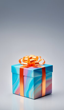 Multicolored gift box with satin ribbon on gray background. Side view of a birthday gift. Vertical photoの素材