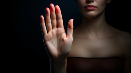 Strong serious young lady extending hand forward forbidding saying no to harassment bullying abuseの素材