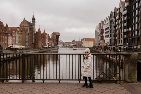 little girl standing on a bridge and looking at the old architecture of Gdansk, Poland