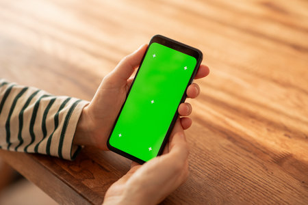 a woman using a green-screen smartphone in her home. High quality photoの写真素材