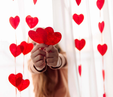 girl holding red hearts on a white background, congratulations on Valentines Dayの写真素材
