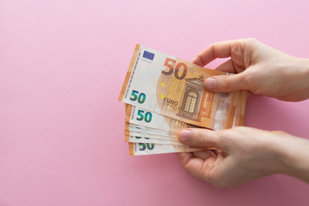 Hands holding euro on a pink background with space for text