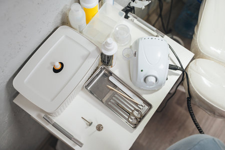 A close-up of a pedicure process with professional manicure tools, including a file and scissors,...