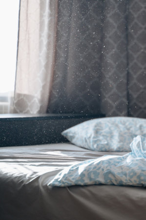 A cozy unmade bed with pollen floating in the golden morning sunlight, creating a dreamy and warm atmosphere, perfect for themes of comfort, relaxation, and serenityの写真素材