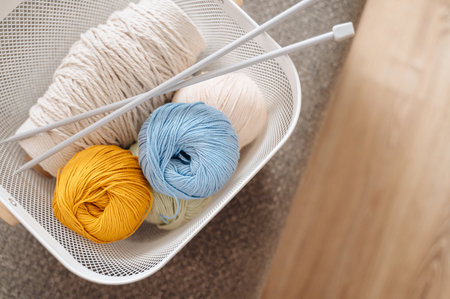 A cozy arrangement of skeins of knitting thread neatly placed in a basket, symbolizing creativity,...