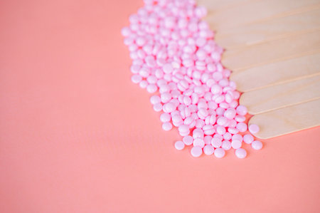 Depilatory wax of pink color, depilatory spatulas, hot wax type, for face and body, pink granules on a pink backgroundの写真素材