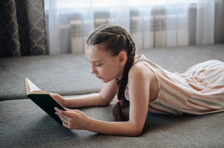 A girl comfortably lying on a sofa, engrossed in reading a book, depicting relaxation