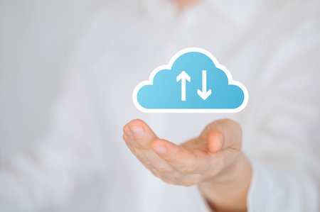 Hand holding digital cloud icon with upload and download arrows, symbolizing data transfer and cloud
