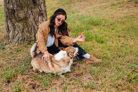 A beautiful woman sits with her Pembroke Corgi outdoors.の写真素材