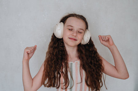 A carefree girl with headphones listens to music and dances.