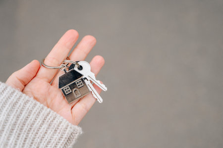 Woman holding apartment keys in front of house.