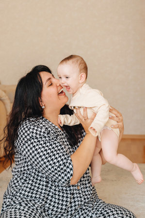 Happy mother spending time with baby at home, family love concept.
