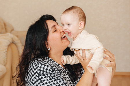 Happy mother spending time with baby at home, family love concept.
