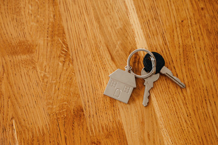 House keys with keychain lying on wooden table, real estate concept.の写真素材