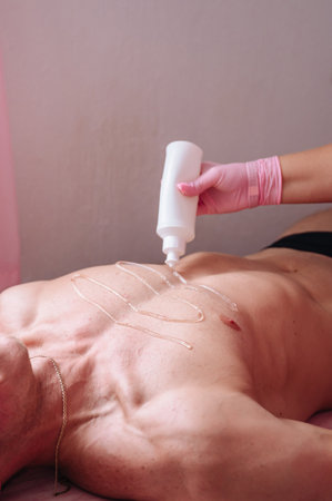 Female specialist performing laser hair removal on male client, salon procedure.の写真素材