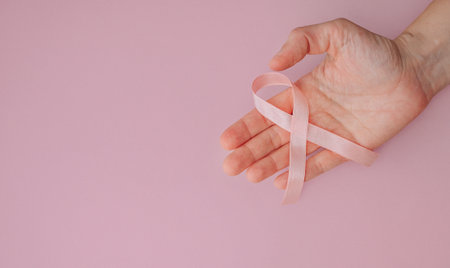Woman holding pink breast cancer awareness ribbon, medical support concept.の写真素材