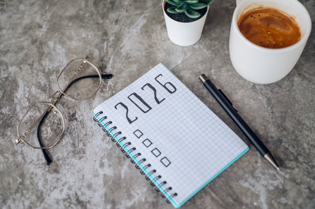 New Year 2026 resolutions list with laptop and coffee cup, goals planning concept.の写真素材