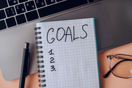 Goals notebook with pen and laptop, productivity and planning concept.の写真素材
