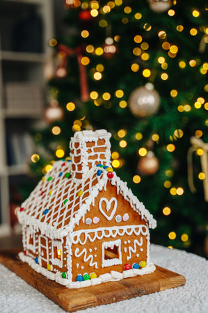 Gingerbread house centerpiece with out-of-focus Christmas tree lights, festive Christmas and New Years mood.の写真素材