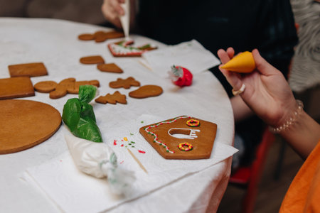 Children happily decorating gingerbread houses with icing and candy for a festive Christmas holiday activity.の写真素材