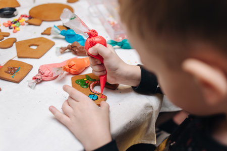 Children happily decorating gingerbread houses with icing and candy for a festive Christmas holiday activity.の写真素材