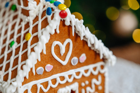 Gingerbread house centerpiece with out-of-focus Christmas tree lights, festive Christmas and New Years mood.の写真素材