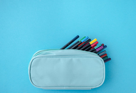 Various stationery tools in pencil case on blue background, school supplies and education...