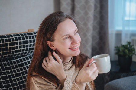 Happy woman smiling and holding mug with hot drink, concept of peace joy and relaxation at home.