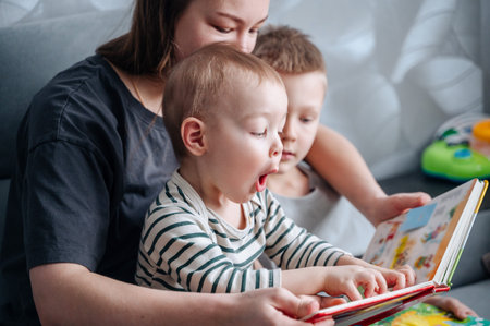 Mother and children reacting emotionally while reading colorful book together, imagination and...