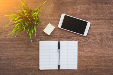 smartphone, notebook and pen on a brown wooden desktopの写真素材
