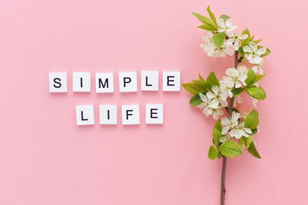 inscription simple life and spring twig of a blossoming tree on a pink backgroundの写真素材