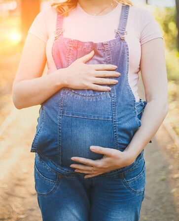 pregnant woman holds her hands on her stomach, her face is not visibleの写真素材