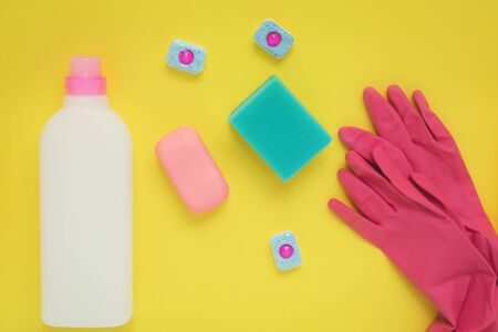 flatlay on a yellow background household chemicals, cleaning products, gloves, soap, dishwasher...