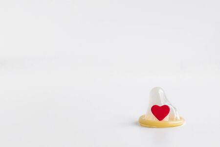 one isolated classic condom without packaging and red small heart on a white background place for text 1の写真素材