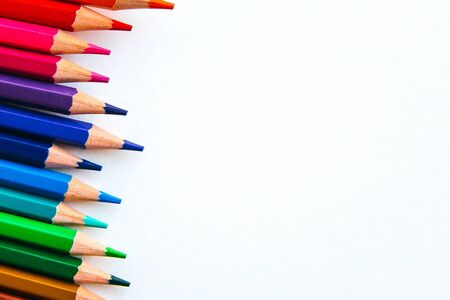 bright multi-colored flat lay pencils for drawing on a white background, place for text
