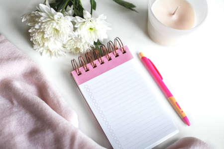 minimalistic pink still life on the table, notebook, flowers, pen, candle comfortの写真素材
