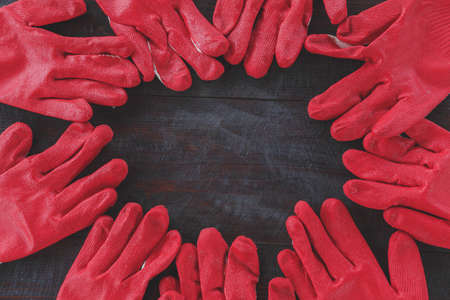 circle of red construction gloves on a dark wooden background 1
