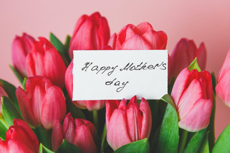 bright beautiful bouquet of pink tulips with a gift card with handwritten Happy Mother's Day.
