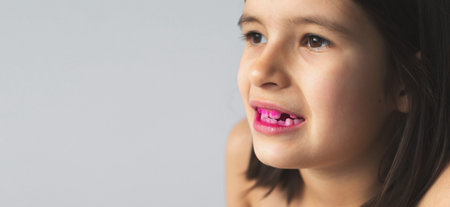 close-up portrait of 7 year old girl with her mouth open and teeth with pink plaque indicator...