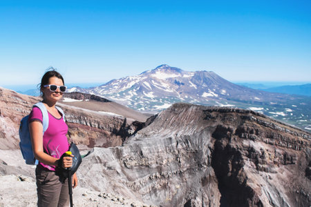 portrait of one girl tourist with backpack and hiking stick climbs volcano in Kamchatka, natural volcanic landscape, adventure and travel concept.の写真素材