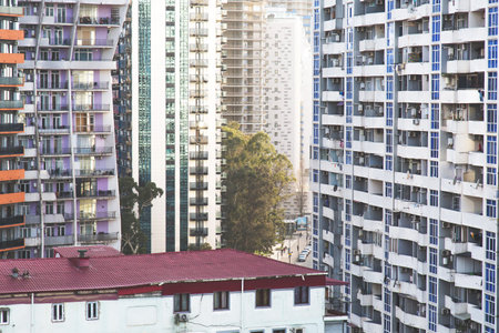 A lot of very different High-rise apartment buildings densely packed in urban area, mix of modern glass towers and older residential blocks, with narrow street and trees between them, urban conceptの写真素材