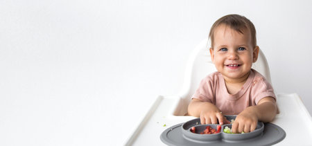 horizontal banner close up portrait beautiful baby 1 year old sitting in a highchair and eating...