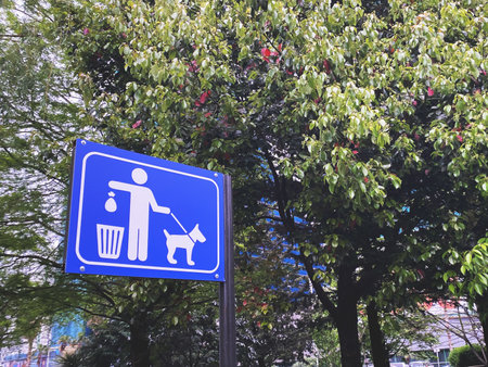 street sign encouraging people to clean up after their dog on a pole in a park.の写真素材
