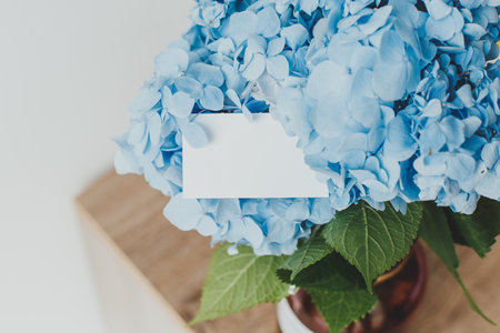 beautiful bouquet of blue hydrangea in a vase and a blank white card for your greeting text, the concept of congratulations on the occasion.の写真素材
