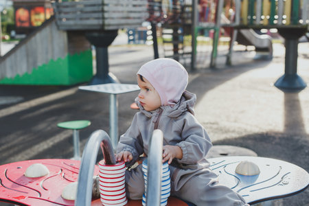 small child 1 year and 3 months old plays on the playground in the park in autumn.の写真素材